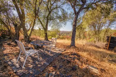 a table and chairs on a stone walkway with trees at Breathtaking view of the Hills with HotTub, Pool and Pool Table in Marble Mountain