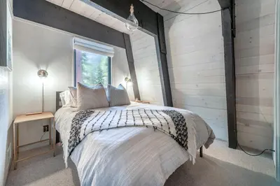 a bedroom with a large bed with a window at Mid Century Modern A-Frame Cabin at Northstar in Truckee