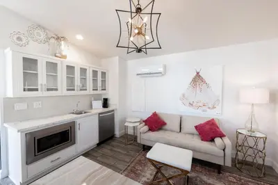 a white living room with a couch and a kitchen at Elegant Courtyard Cottage Ruby in Reno