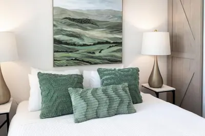 a bedroom with a bed with green pillows and a painting at Cottage on Historic Grounds Jade in Reno