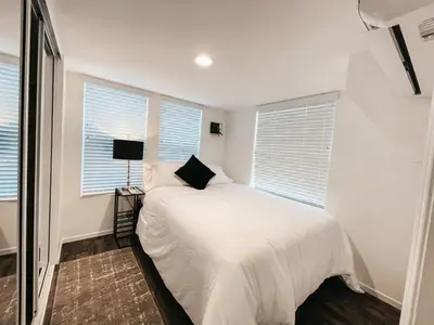 a bedroom with a bed with white sheets and windows at Beautiful Downtown Cottage Onyx in Reno