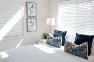 a bedroom with a bed with blue pillows and a window at Beautiful Cottage on Historic Grounds in Reno