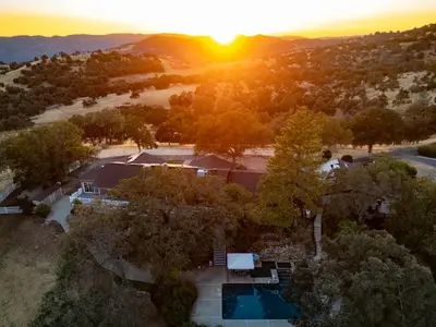 an aerial view of a house with a pool and the sunset at Yosemite Mountain Top - Treetop Villa in Mariposa