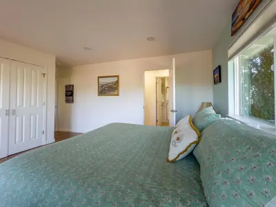 a bedroom with a bed with a green comforter and a window at Yosemite Mountain Top - Treetop Villa in Mariposa
