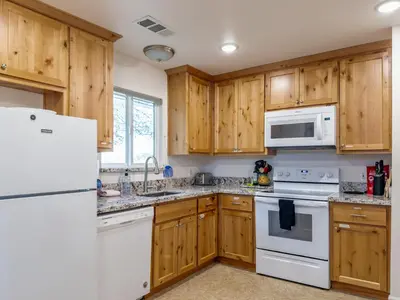 a kitchen with wooden cabinets and white appliances at Yosemite Mountain Top - Treetop Villa in Mariposa