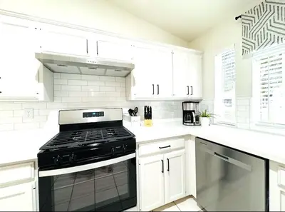 a kitchen with white cabinets and a black stove at Charming retreat in CA Valley in Fresno