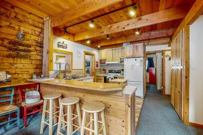 a kitchen with wooden walls and a counter with bar stools at The Calder Cabin in Soda Springs