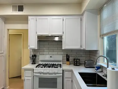 a kitchen with white cabinets and a stove top oven at Remodeled 3B2B Bright House with a King Suite in Sacramento