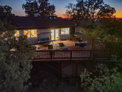 a house with a deck with a sunset in the background at Yosemite Mountaintop Retreat on 100 acres, 2 Homes, 2 hot tubs, pool in Mariposa