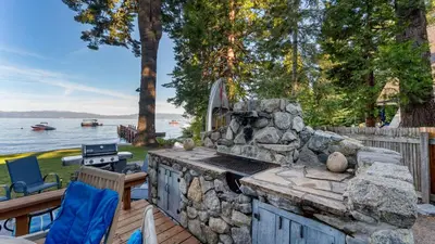 a stone fireplace on a deck with a table and chairs at Lakefront Haven by AvantStay Minutes to Ski Resorts Private Dock in Homewood