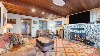 a living room with a stone fireplace and a flat screen tv at Lakefront Haven by AvantStay Minutes to Ski Resorts Private Dock in Homewood