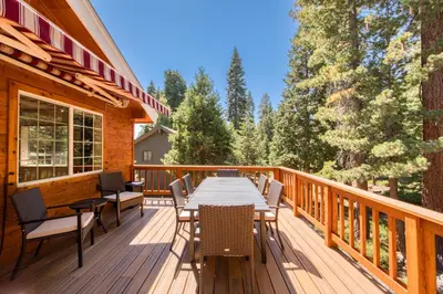 a wooden deck with a table and chairs on it at Knotty and Nice - 4BR w Private Hot Tub, Close to Lake in Tahoe Vista