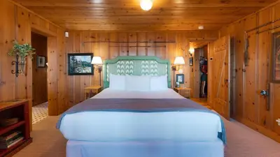 a bedroom with a large bed in a wooden room at Homewood Lakefront by AvantStay Private Beach Lake Access Views in Homewood