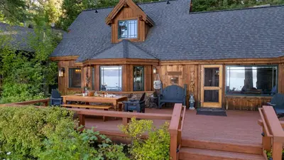 a log cabin with a wooden deck with a table and chairs at Homewood Lakefront by AvantStay Private Beach Lake Access Views in Homewood