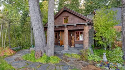 a log cabin in the woods with trees at Homewood Lakefront by AvantStay Private Beach Lake Access Views in Homewood