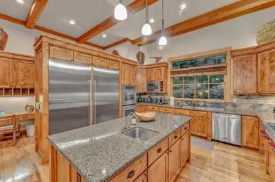 a kitchen with wooden cabinets and a stainless steel refrigerator at Northstar Ski-In Ski-Out with Valley Views in Ponderosa Fairway Estates