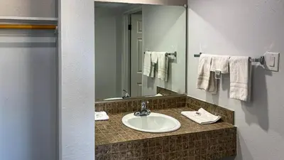 a bathroom with a sink and a mirror and towels at Motel 6 Selma, CA in Selma
