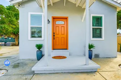 a white house with an orange door and two plants at Small-Town Charm and Patio Dining Home in Madera! in Madera