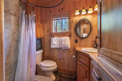 a bathroom with a toilet and a sink and a mirror at Home for 10 Private Hot-Tub Close to Ski Private Beach Access w Double Decker pier Book on Mobile for Promo Price in Carnelian Bay