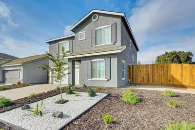 a gray house with a wooden fence in a yard at Chowchilla Home with Private Patio! in Chowchilla