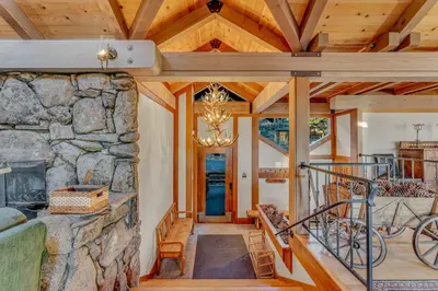 a living room with a stone wall and a staircase at 3-Level Getaway Minutes from Lake Tahoe in Tahoe City