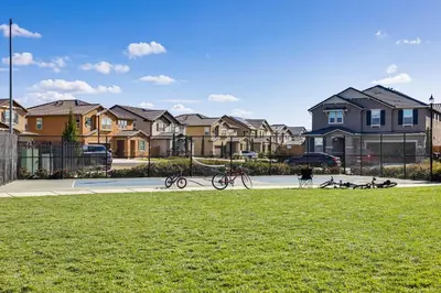a person walking a bike on a court with houses at WFH-Friendly Getaway with Yard in Manteca! in Manteca