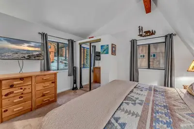 a bedroom with a bed and a dresser and windows at White Fir Chalet Dog Friendly Cabin in the Woods in Soda Springs