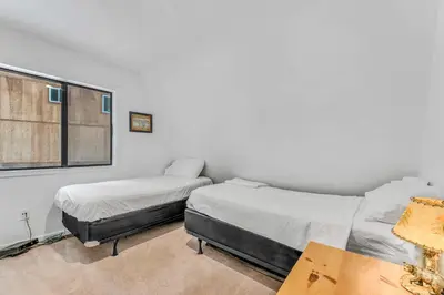 two beds in a white room with a window at White Fir Chalet Dog Friendly Cabin in the Woods in Soda Springs