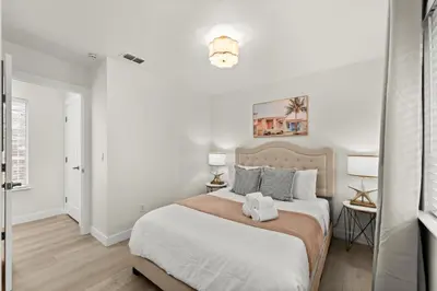 a white bedroom with a large bed and two lamps at Recently Upgraded House with King Suite, quiet NBHD, Fast Wifi, and Yard in Elk Grove