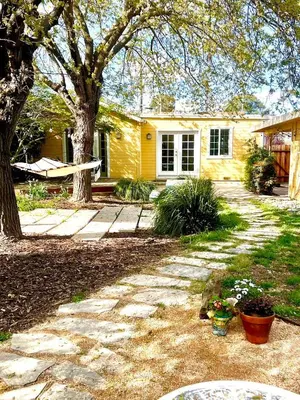 a yellow house with a tree in the yard at 2 Private Bedroom Suites with Hot Tub in Sacramento