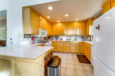 a kitchen with wooden cabinets and a white refrigerator at Snowshoe and Sled On-Site! Soda Springs Cabin in Soda Springs