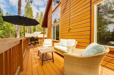 a porch with wicker chairs and an umbrella at Snowshoe and Sled On-Site! Soda Springs Cabin in Soda Springs
