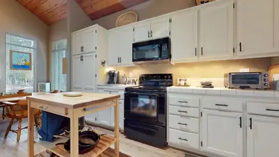 a kitchen with white cabinets and a wooden table at Snowcreek IV #545 condo in Mammoth Lakes