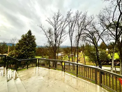 a balcony with a wooden railing and a tree at Modern Yosemite Cabin, 15min Bass Lake, Sleeps 8 in Oakhurst