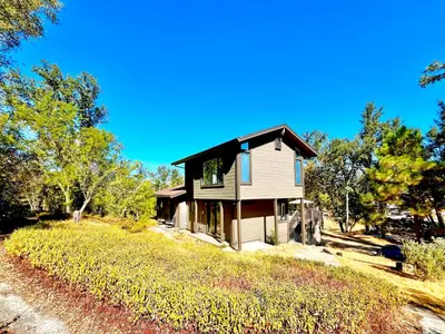 a house on top of a grassy hill at Modern Yosemite Cabin, 15min Bass Lake, Sleeps 8 in Oakhurst