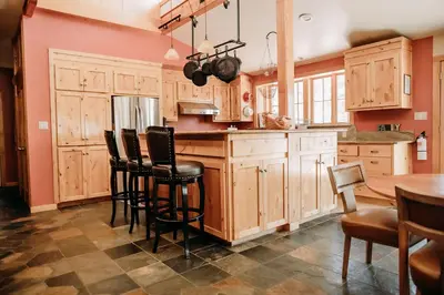 a kitchen with wooden cabinets and a table and chairs at Oak Meadows House - A unique home near Yosemite in Mariposa