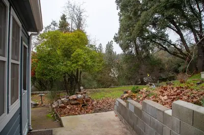 a yard with a retaining wall next to a house at Yosomite Gateway Historic Victorian with Modern Touch in Sonora