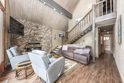 a living room with a couch and a stone wall at Elderberry Bluejay Location Goals Tub Time in Shaver Lake