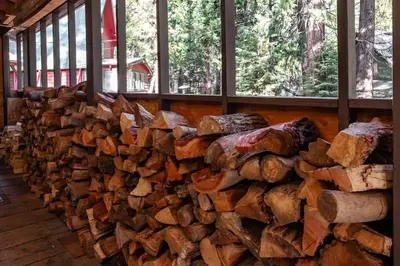 a pile of logs in a room with windows at Elderberry Bluejay Location Goals Tub Time in Shaver Lake