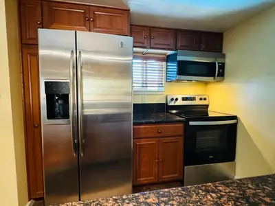 a stainless steel refrigerator in a kitchen with wooden cabinets at Cozy Condo in Mammoth with 2 parking spots! Ski,Snowboard, Ice skate! in Mammoth Lakes