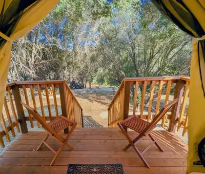 a porch with two chairs on a wooden deck at Wildhaven Yosemite Glamping in Mariposa