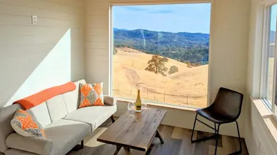 a living room with a couch and a table and a window at Wildhaven Yosemite Glamping in Mariposa