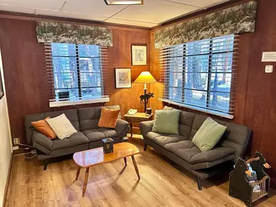 a living room with two couches and a table at 1B Heart of the Meadow at The Redwoods In Yosemite in North Wawona