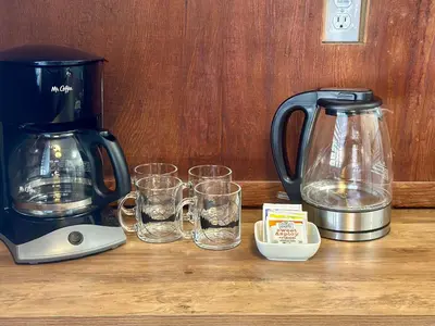 a coffee maker and glasses on a wooden table at 1B Heart of the Meadow at The Redwoods In Yosemite in North Wawona