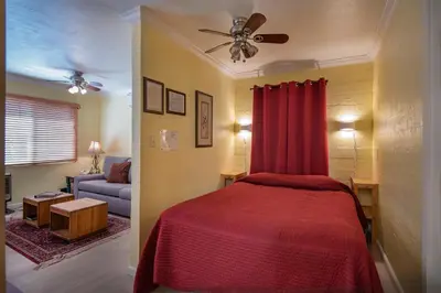 a bedroom with a red bed and a couch at Riverfront Retreat in North Wawona
