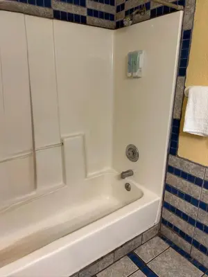 a white bath tub in a bathroom with blue tiles at Cinderella Motel in Hollister