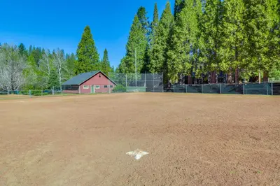 an empty baseball field with a fence and trees at Fire Pit, Gazebo and Grill Family Cabin in Arnold! in Arnold