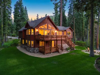 a large log cabin in the woods with a deck at Eagle Rock By Tahoe Getaways - 4BR West Shore w Hot Tub & Close to Hiking! in Homewood