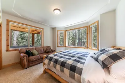 a bedroom with a bed and a couch and windows at Eagle Rock By Tahoe Getaways - 4BR West Shore w Hot Tub & Close to Hiking! in Homewood