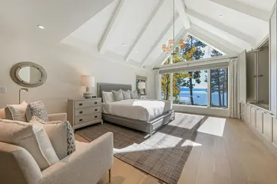 a bedroom with a bed and a couch and a window at Spellbound Lakefront Lodge by Tahoe Getaways - 5 BR w Hot Tub, Buoy & Beach access in Kings Beach
